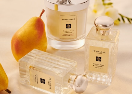 English Pear and Freesia colognes and candle on a table with a pear